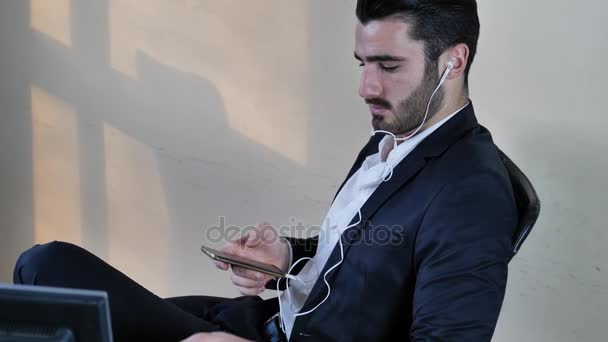 Бизнесмен с наушниками, слушающий музыку — стоковое видео