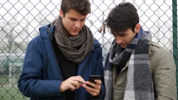 Dois jovens lendo mensagem de texto ou navegando na web — Vídeo de Stock