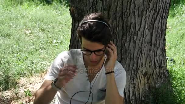 Young Man Listening to Music in Park — Stock Video