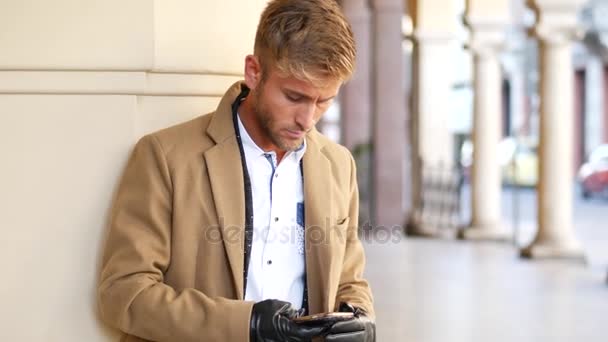 Hombre de moda guapo usando el teléfono celular para escribir texto — Vídeos de Stock