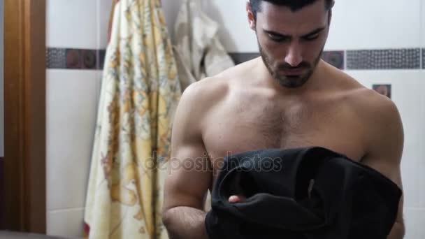 Привабливий м'язистий молодий чоловік одягається у ванну кімнату — стокове відео