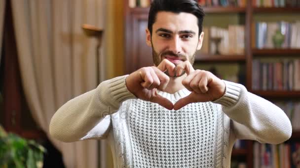 Красивий молодий чоловік робить знак серця руками — стокове відео