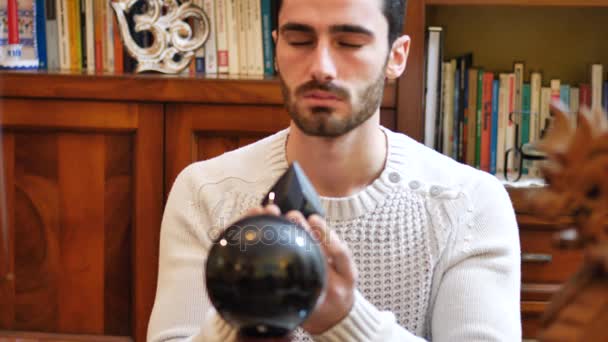 Молодой мужчина-провидец предсказывает будущее, глядя в хрустальный шар — стоковое видео