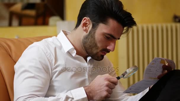 Young Man Examining Contract or Bill with Magnifying Glass — Stock Video