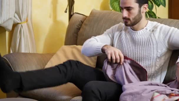 Mladý muž sedí na pohovce u televize pod dekou — Stock video