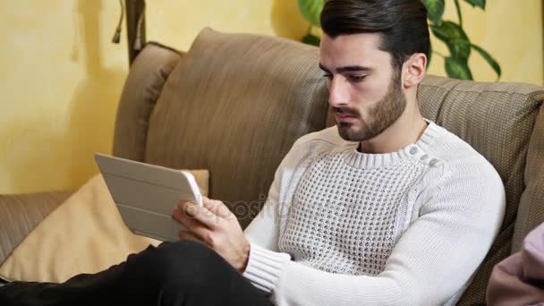 Joven guapo en casa, usando tableta PC — Vídeo de stock