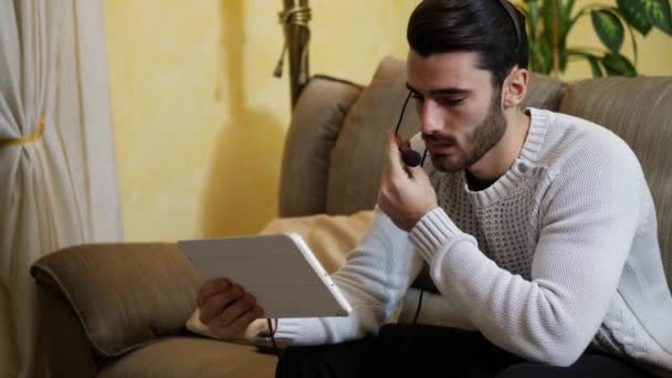 Hombre sentado en el interior de chat de vídeo con la tableta PC — Vídeos de Stock