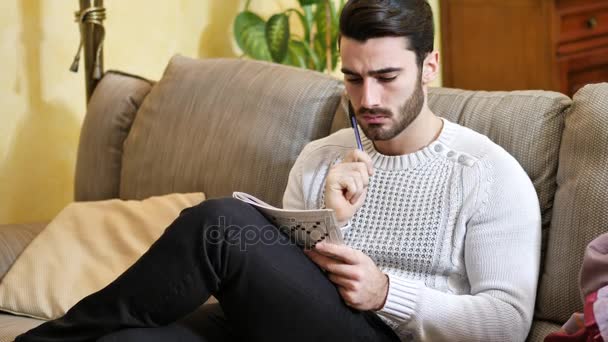 Jeune homme assis faisant un puzzle de mots croisés — Video