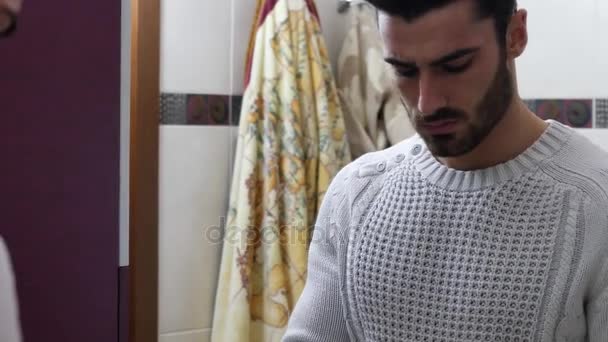 Hombre joven guapo aplicando crema hidratante en la cara — Vídeo de stock