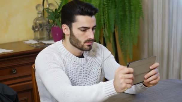 Концентрированный человек играет с планшетным ПК — стоковое видео