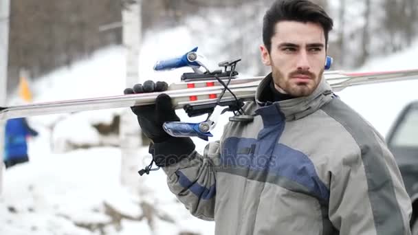 Hombre guapo con esquí caminando en la nieve — Vídeos de Stock