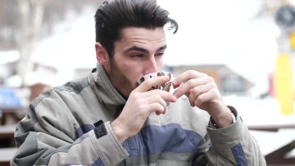 Młody narciarz picia gorącej kawy poza — Wideo stockowe