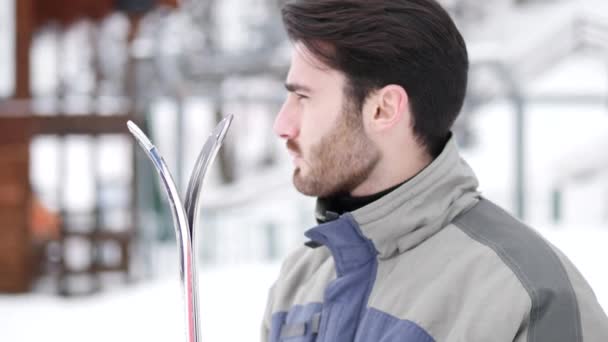 Όμορφος άνδρας με σκι στέκεται στο χιόνι — Αρχείο Βίντεο