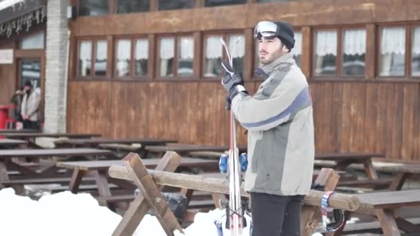Hombre guapo con esquí de pie en la nieve — Vídeo de stock