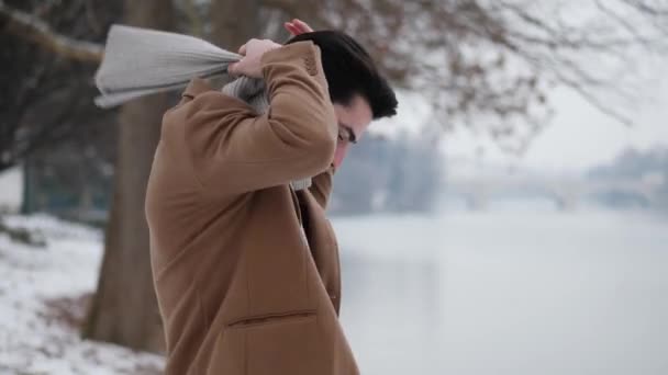Молодой человек в снежном городе надевает перчатки — стоковое видео