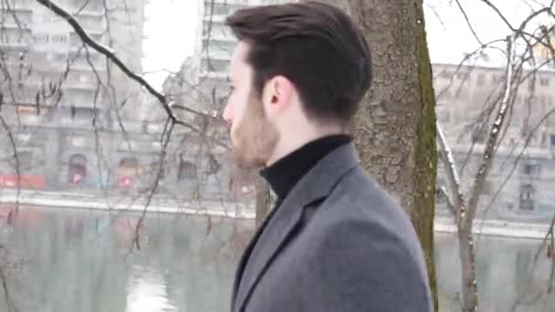 Mladý muž v zasněžené městském parku — Stock video