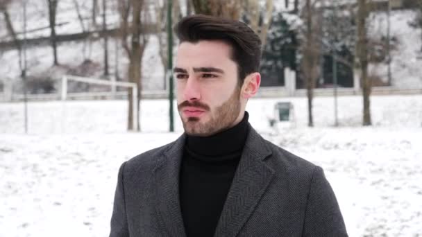 Young man in snowy city park — Stock Video