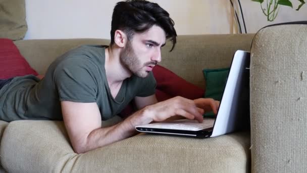 Jovem fazendo lição de casa no laptop no sofá — Vídeo de Stock