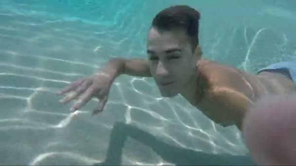 Bonito jovem nadando na piscina, tiro subaquático — Vídeo de Stock