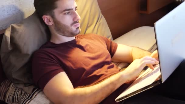 Giovane uomo che fa i compiti sul computer portatile in camera da letto — Video Stock