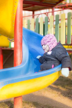 Küçük kız oyun alanında oynuyor.