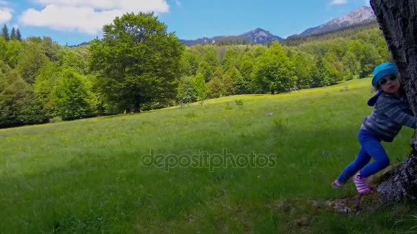 Маленька дівчинка грає на зеленій траві в горах — стокове відео
