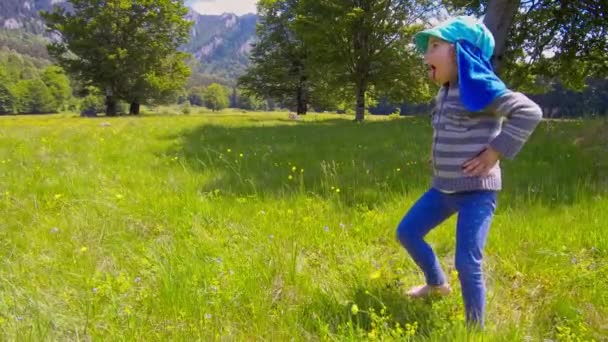 Маленька дівчинка грає на зеленій траві в горах — стокове відео