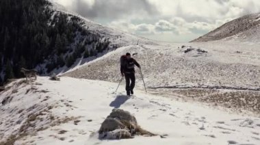 Sırt çantasıyla dağ sırtında yürüyen, derin karla kaplı bir yürüyüşçü.