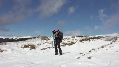 Sırt çantalı, dağ sırtında yürüyen, derin karla kaplı bir fotoğrafçı.