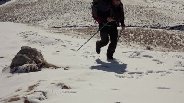 深い雪で覆われた山の尾根を歩くバックパック付きハイカー — ストック動画