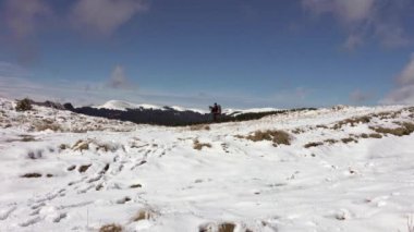 Sırt çantalı, dağ sırtında yürüyen, derin karla kaplı bir fotoğrafçı.