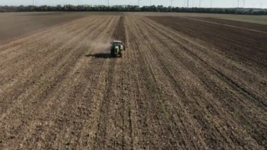 Rüzgâr türbinleriyle benekli bir tarlanın yakınındaki kar temizleyen traktörün hava görüntüsü.