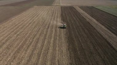 Rüzgâr türbinleriyle benekli bir tarlanın yakınındaki kar temizleyen traktörün hava görüntüsü.