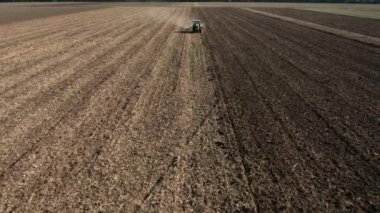 Rüzgâr türbinleriyle benekli bir tarlanın yakınındaki kar temizleyen traktörün hava görüntüsü.