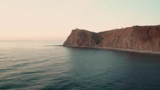 在日出时分 在埃米纳角灯塔上空的无人机飞行 四周环绕着碧绿的大海和山坡 保加利亚黑海海岸 — 图库视频影像