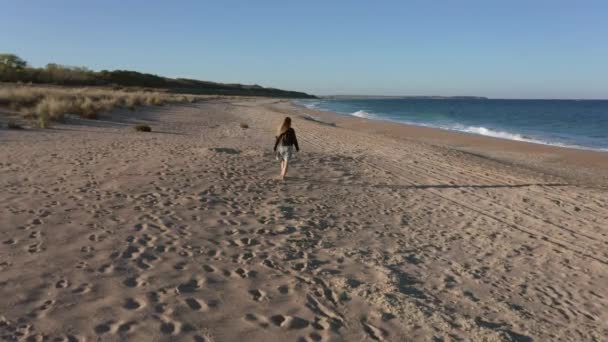 一个金发碧眼的年轻女子在日落前漫步在美丽的热带沙滩上的视频 — 图库视频影像