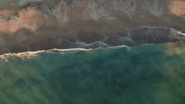 Vol par drone au-dessus de la plage sauvage et de la mer verte turquoise, au-dessus des vagues et du sable 