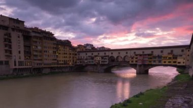İtalya, Floransa 'daki Arno Nehri üzerindeki ünlü Ponte Vecchio' nun gün batımı manzarası, gece gündüz. Kapat..