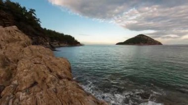 Thasos adasının kayalık kıyı şeridinde gün batımında zaman kaybı ve Yunanistan 'ın Nisida Kinira adasına bakış