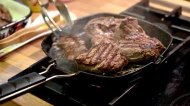 Izgara tavada baharatlı çiğ dana bifteğinin yakın çekim videosu.