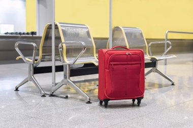 Havaalanı terminalinin varış salonunda kırmızı bavul. Seçici odak.