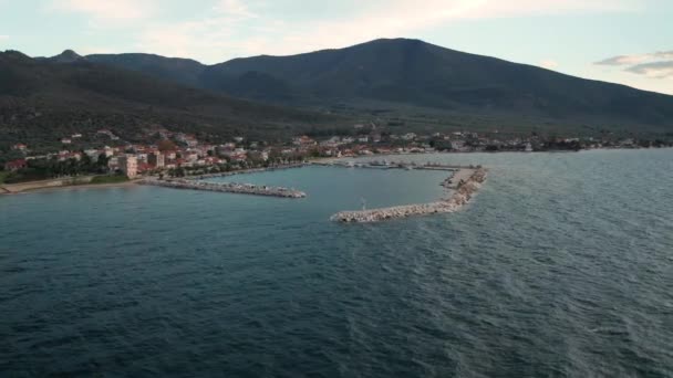 ギリシャのThasos島の岩場の海岸線で停泊船と小さな村のマリーナのアリアルビデオ日没 — ストック動画