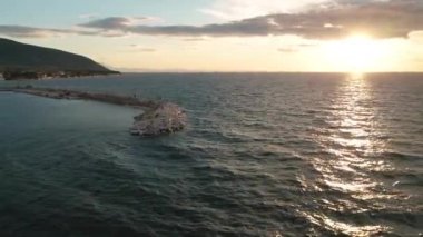 Yunanistan 'ın Thasos adasının kayalık kıyı şeridinde gün batımında küçük bir marina limanına demir atmış.