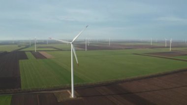 Bahar tarlaları boyunca rüzgar türbinlerinin etrafında uçan hava. Temiz ve Yenilenebilir Rüzgâr Güç Çiftliği hareket halinde. Yeşil enerji, sürdürülebilir alternatif elektrik, kirlilik ortamı yok.