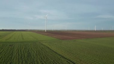 Bahar tarlaları boyunca rüzgar türbinlerinin etrafında uçan hava. Temiz ve Yenilenebilir Rüzgâr Güç Çiftliği hareket halinde. Yeşil enerji, sürdürülebilir alternatif elektrik, kirlilik ortamı yok.