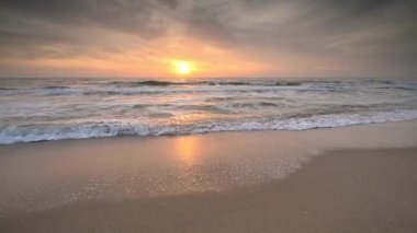 Güneş doğarken kumlu bir sahilin renkli yakın görüntüsüne sahip bir video.