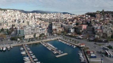 Yunanistan 'ın kuzeyindeki Kavala şehrinin üzerinde insansız hava aracı uçuşu, kırmızı çatıları ve ortaçağ şehir duvarlı evler, eski su kemerleri Kamares ve botlu marina.