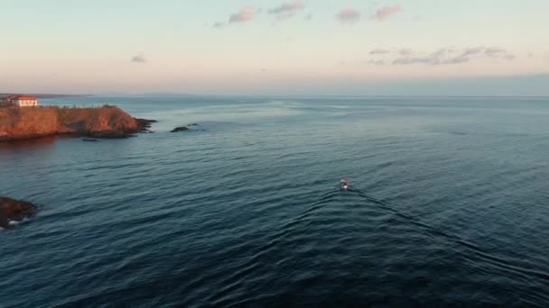 Un vol de drone au lever du soleil au-dessus d'un petit bateau entrant dans la mer, Ahtopol, côte de la mer Noire, Bulgarie 