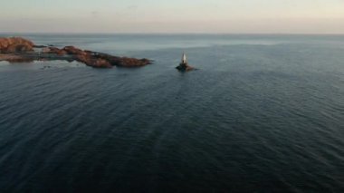 Bulgaristan 'ın Karadeniz kıyısındaki Ahtopol limanındaki deniz fenerinin etrafında gün doğumunda insansız hava aracı uçuşu