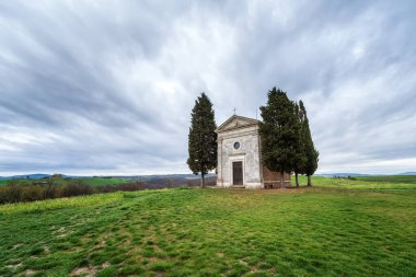 Yeşil yuvarlanan tepeleri ve sabahları Toskana 'nın göbeğindeki Pienza yakınlarındaki Vitaleta şapeli ile muhteşem bir bahar manzarası.